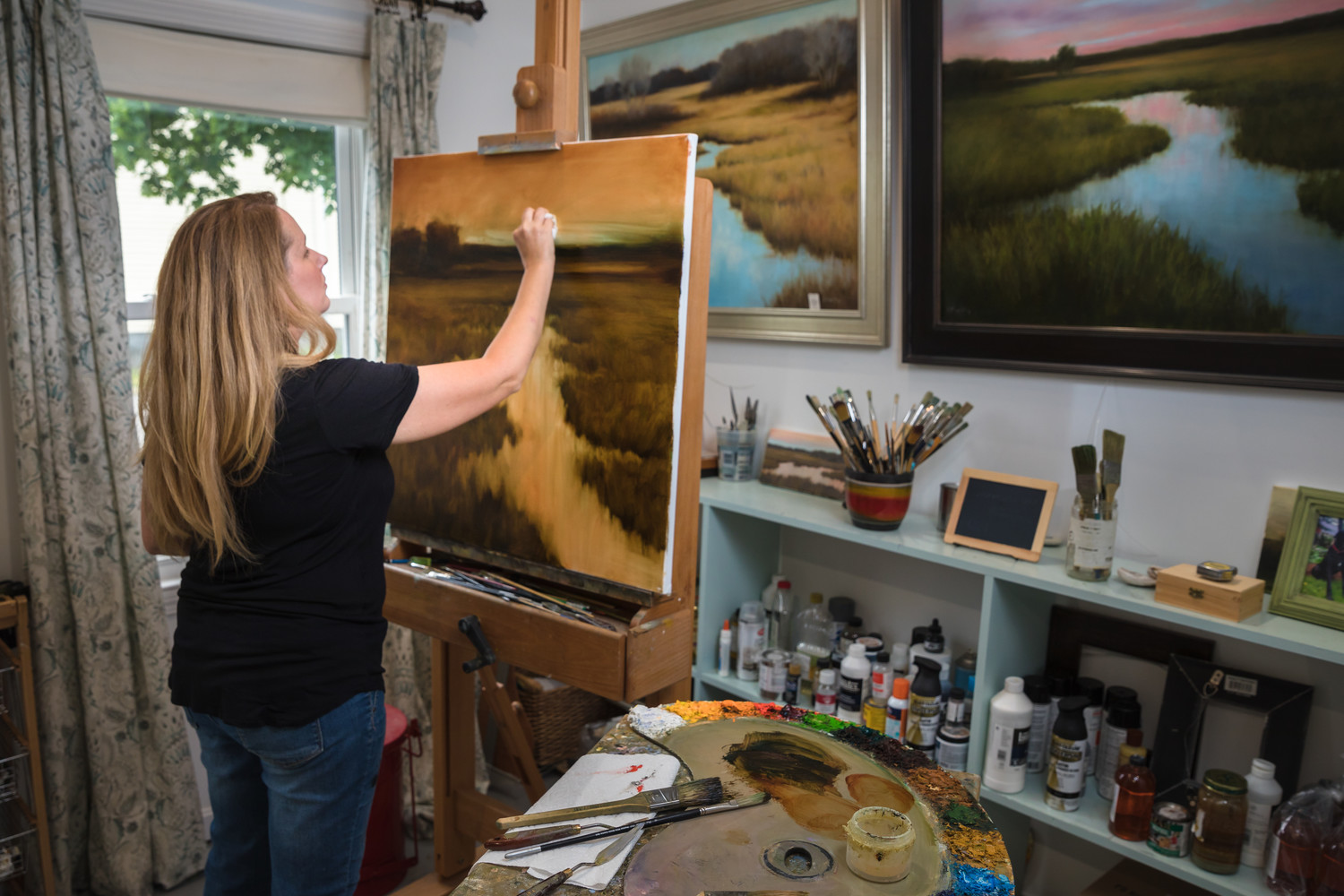 Artist Karen Murphy painting an East Bay inspired landscape to add to her collection in her East Providence studio.